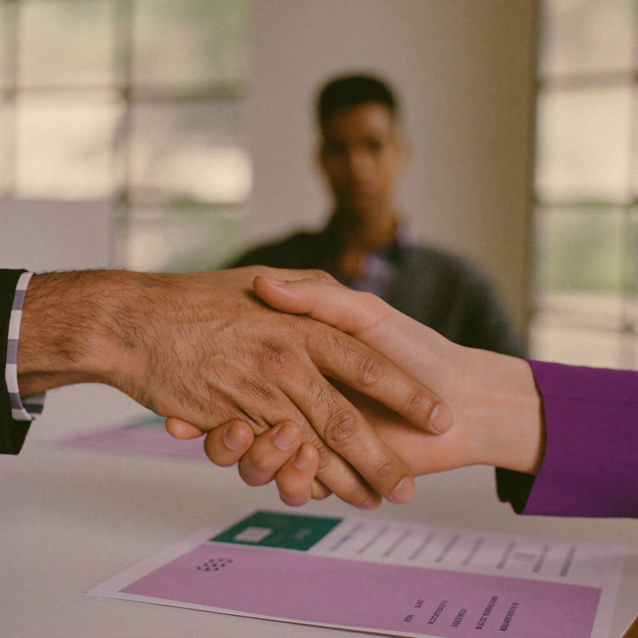 Two people shaking hands over a partnership agreement